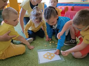 Mała grupa dzieci układa plaster miodu z papieru.