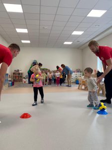 Dzieci ustawione w 2 rzędach biegną do piłki razem z 2 sportowcami.