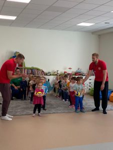 Dzieci ustawione w 2 rzędach stoją razem z 2 sportowcami.