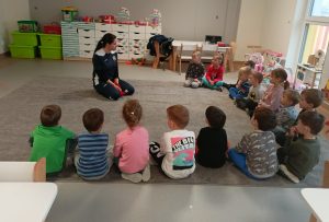 Dzieci chodzą po dywanie i nogami leciutko popychają piłkę.