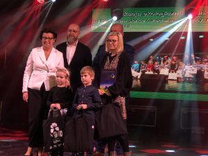 Dziewczynka, chłopiec oraz nauczycielka trzmający w rękach torby. Nauczycielka trzyma w rękach teczkę. Z tyłu stoi Pani Senator, Wiceprezydent Miasta oraz mężczyzna.