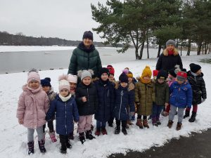 Dzieci i panie pozują do zdjęcia przy jeziorze