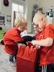 Trzech chłopców pakujący artykuły spożywcze do kartonu.