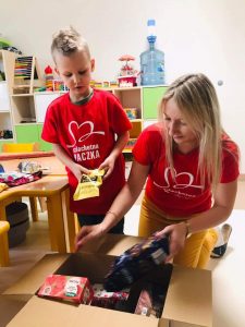 Pani wtraz z chłopcem umieszczający artykuły spożywcze do kartona.