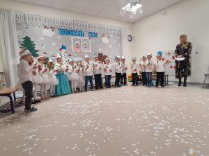 Dzieci trzymają w rękach kwiaty i upominek dla babci i dziadka