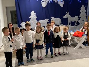 Grupa dzieci w rzędzie. Jeden chłopiec trzyma mikrofon.