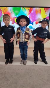 Dwóch chłopców przebranych za Policjantów , po środku nich stoi chłopiec przebrany za Kowboja.