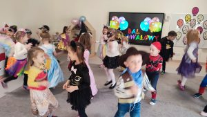 Dzieci w strojach karnawałowych tańczą do muzyki .