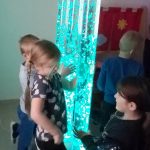 Dzieci stoją przy niebieskiej tubie z bąbelkami.