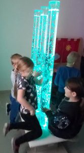Dzieci stoją przy niebieskiej tubie z bąbelkami.