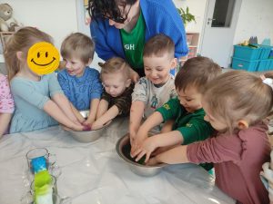 DZIECI WYRABIAJĄ RĄCZKAMI MASĘ TĘCZOWĄ
