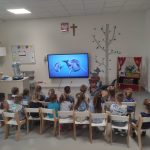 DZIECI OGLĄDAJĄ FILM DOKUEMNTALNY O DELFINACH NA TABLICY MULTIMEDIALNEJ