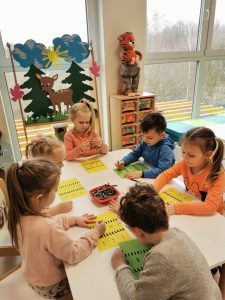 Dzieci przy stolikach wykonują pracę plastyczną