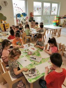 Dzieci przy stolikach wykonują pracę plastyczną
