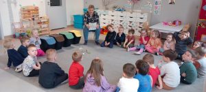 Dzieci i nauczycielka siedzą w kole na dywanie