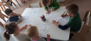 Dzieci przy stolikach wykonują pracę plastyczną