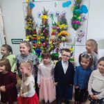 Dzieci stoją na tle palm wielkanocnych. Wszystkie dzieci brały udział w konkursie.