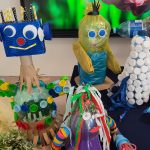 Na granatowym materiale stoją zabawki wykonane z odpadów kartonowych, plastikowych itd.
