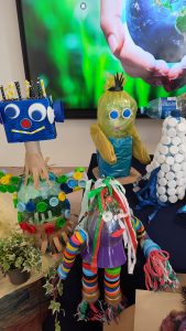 Na granatowym materiale stoją zabawki wykonane z odpadów kartonowych, plastikowych itd.