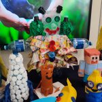 Na granatowym materiale stoją zabawki wykonane z odpadów kartonowych, plastikowych itd.