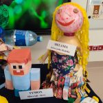 Na granatowym materiale stoją zabawki wykonane z odpadów kartonowych, plastikowych itd.