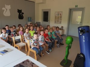Dzieci słuchające pana astronoma stojącego pogadanki o kosmosie