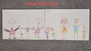 Na szarym dywanie leżą obok siebie 2 rysunki przedstawiające rodzinę (postaci mamy, taty, i dzieci).