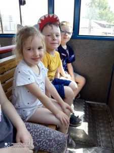4 dzieci chłopcy i dziewczynki siedzą na drewnianej ławce i wyglądają przez okno kolejki.
