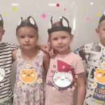 Dwie dziewczynki i dwóch chłopców stoją obok siebie, przytulają się i są uśmiechnięci. Na głowie mają uszy kocie.
