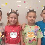 Dwie dziewczynki i dwóch chłopców stoją obok siebie, przytulają się i są uśmiechnięci. Na głowie mają uszy kocie.