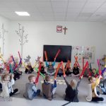 Dzieci siedzą na szarym dywanie i grają na kolorowych ,, bum bum rurkach".