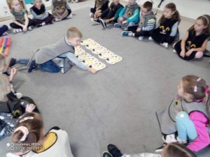 Na szarym dywanie chłopiec układa napis ,,Dzień Muzyki".