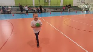 Dziewczynka biegnie z zieloną piłką.