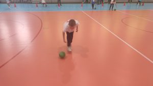 Chłopiec turla piłkę po podlodzwe.