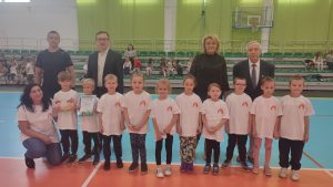 Dzieci pozują do zdjęcia z organizatorami zawodów sportowych.