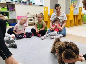 Dzieci siedzą w kole. Biorą udiał w zajęciach dogoterapii.