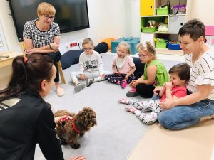 Dzieci siedzą w kole. Biorą udiał w zajęciach dogoterapii.
