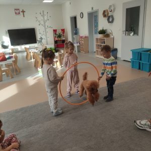 PIES PRZESKAKUJE PRZEZ OBRĘCZA TRZYMANĄ PRZEZ DZIECI