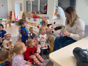 Dzieci słuchają bajki czytanej przez panią bibliotekarkę