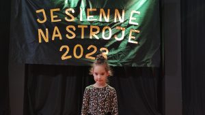 Dziewczynka w czarnej spódniczce i bluzce w brązowe ciapki stoi na scenie MDK i pozuje do zdjęć.