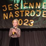 Dziewczynka w czarnej spódniczce i bluzce w brązowe ciapki stoi na scenie MDK i wykonuje piosenkę ,, Jesienna poleczka".