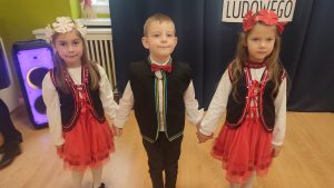 3 trójki dzieci w strojach ludowych stoi na parkiecie i rozpoczyna taniec.