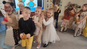 Dzieci przebrane w stroje misiów bawi się do muzyki w sali przedszkolnej.