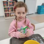 DZIEWCZYNKA POZUJE DO ZDJĘCIA Z WYKONANĄ PRACĄ