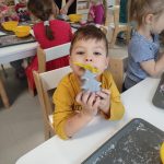 CHŁOPIEC POZUJE DO ZDJĘCIA Z WYKONANĄ PRACĄ