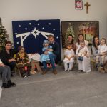 Na zdjęciu, na tle dekoracji Bożonarodzeniowej rodzice z dziećmi. Zdjęcie pamiątkowe.