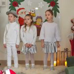 Troje dzieci śpiewa piosenkę Dzieci są w strojach białych.