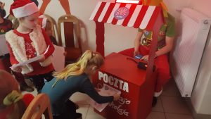 Dziewczynka wrzuca list do poczty Św. Mikołaja.