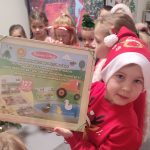 Chłopiec w czerwonej czapce Mikołaja pokazuje prezent- grę.