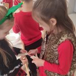 Dzieci w strojach świątecznych dzielą się opłatkiem i składają sobie życzenia.